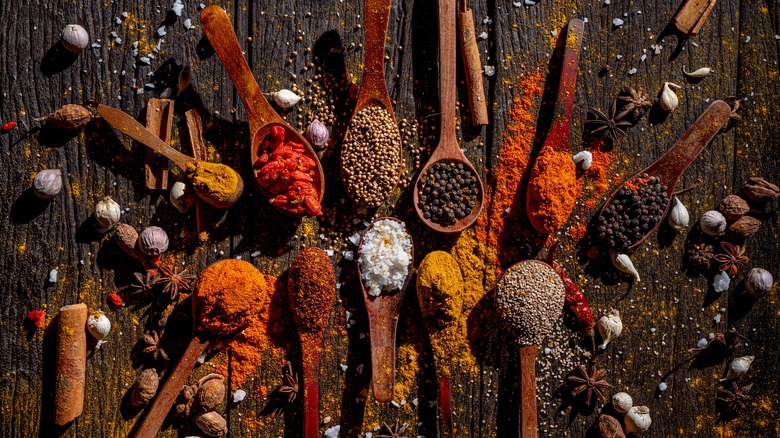 Various whole and powdered spices in wooden spoons