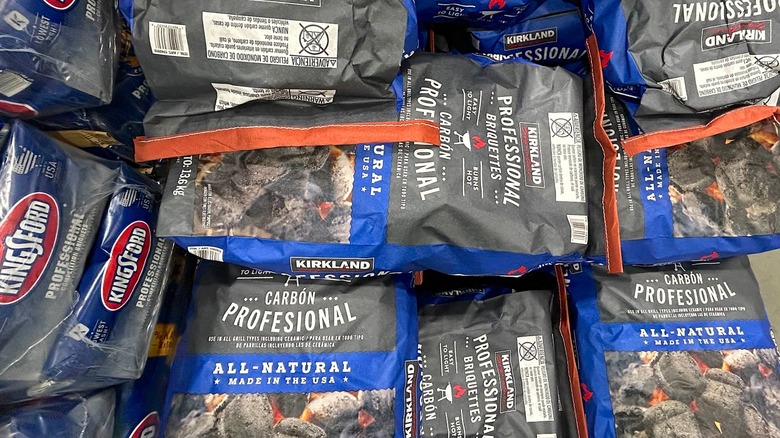 Multiple bags of Kirkland Signature Professional Charcoal Briquettes stacked on top of one another