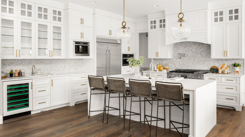 White kitchen with pricey upgrades, such as a pot filler faucet, professional-grade range, steam oven, and built-in coffee system