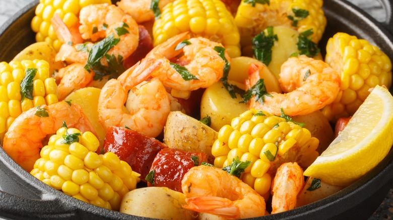 Seafood boil with shrimp, sausage, corn, and potatoes in a cast iron pot