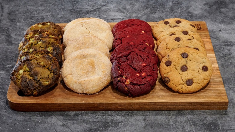 A wooden tray with four different types of cookies