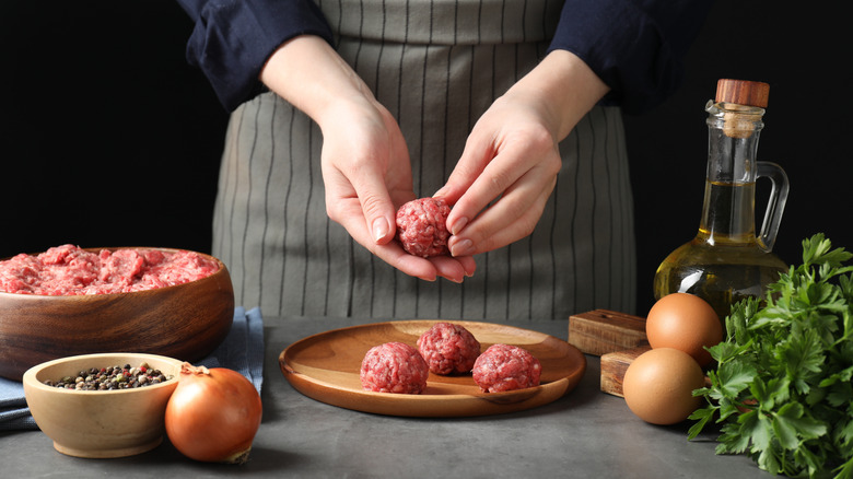 woman making fresh meatballs with ground beef
