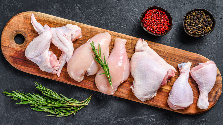 Various cuts of raw chicken on wooden board