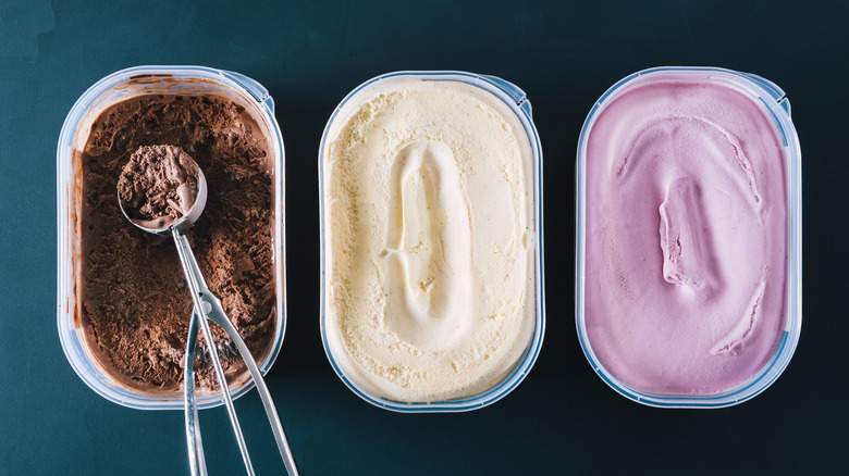 Three containers of frozen yogurt or ice cream with one scoop.
