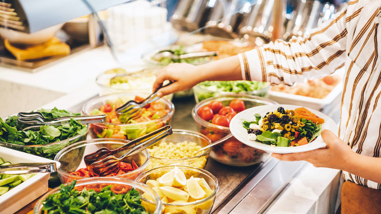 Person making salad at food buffet