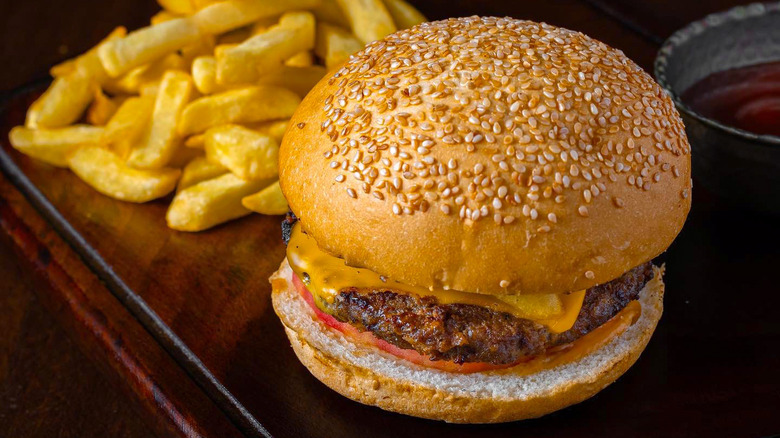Cheeseburger with fries and ketchup on wooden surface