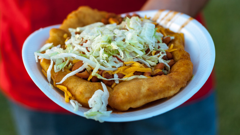 Person holding fry-bread taco on a plate