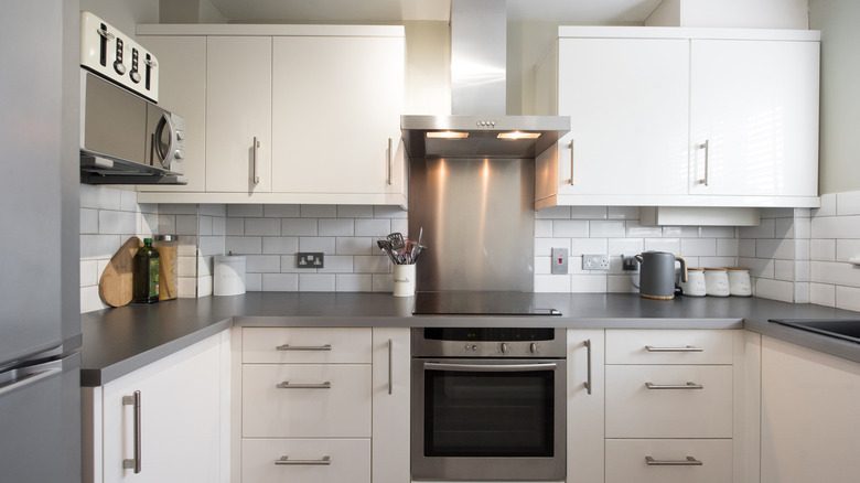 A spotless kitchen with white cabinets and backsplash