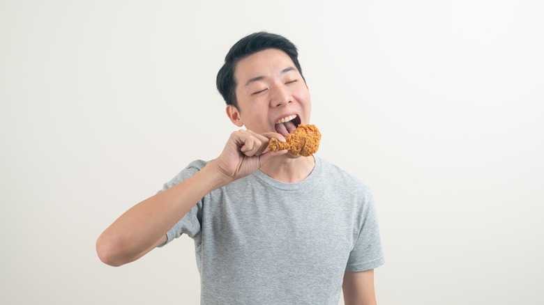 A man cheerfully eating fried chicken