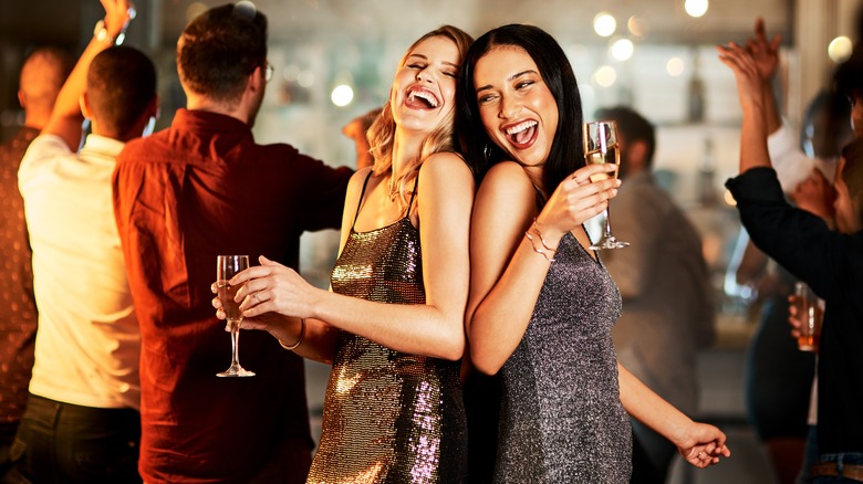 Women dancing at a nightclub, holding Champagne flutes