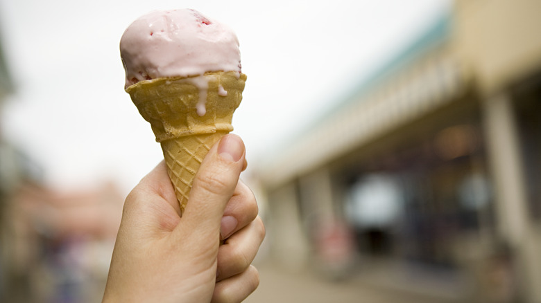 Hand holding a melty ice cream cone