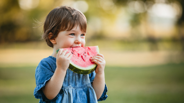 A child eating a big slice of watermelon