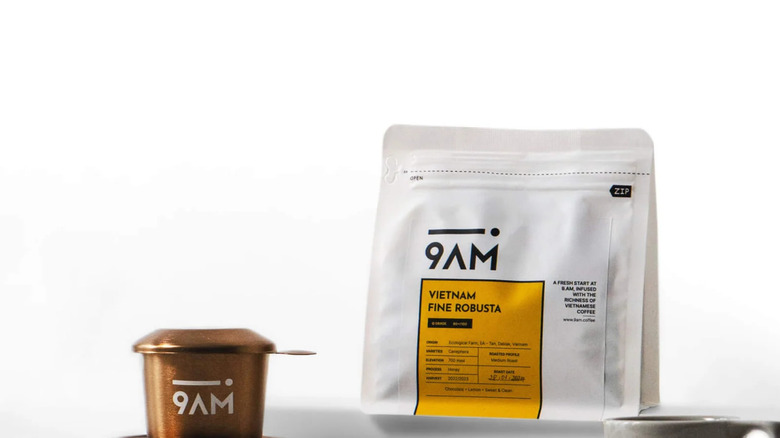 A bag of 9AM Vietnam Fine Robusta next to coffee cups on white background