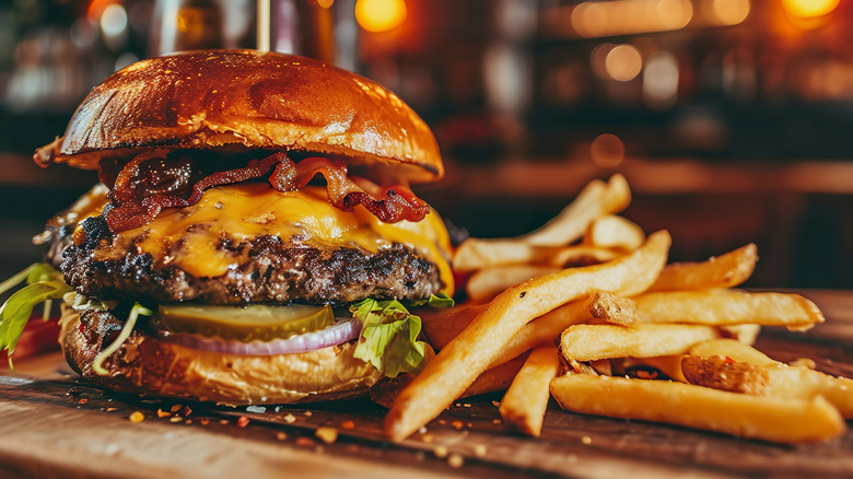 Beef burger stacked with cheese, bacon, and fresh vegetables.