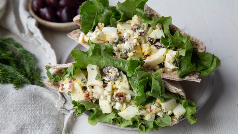 egg salad on lettuce next to a bowl of olives